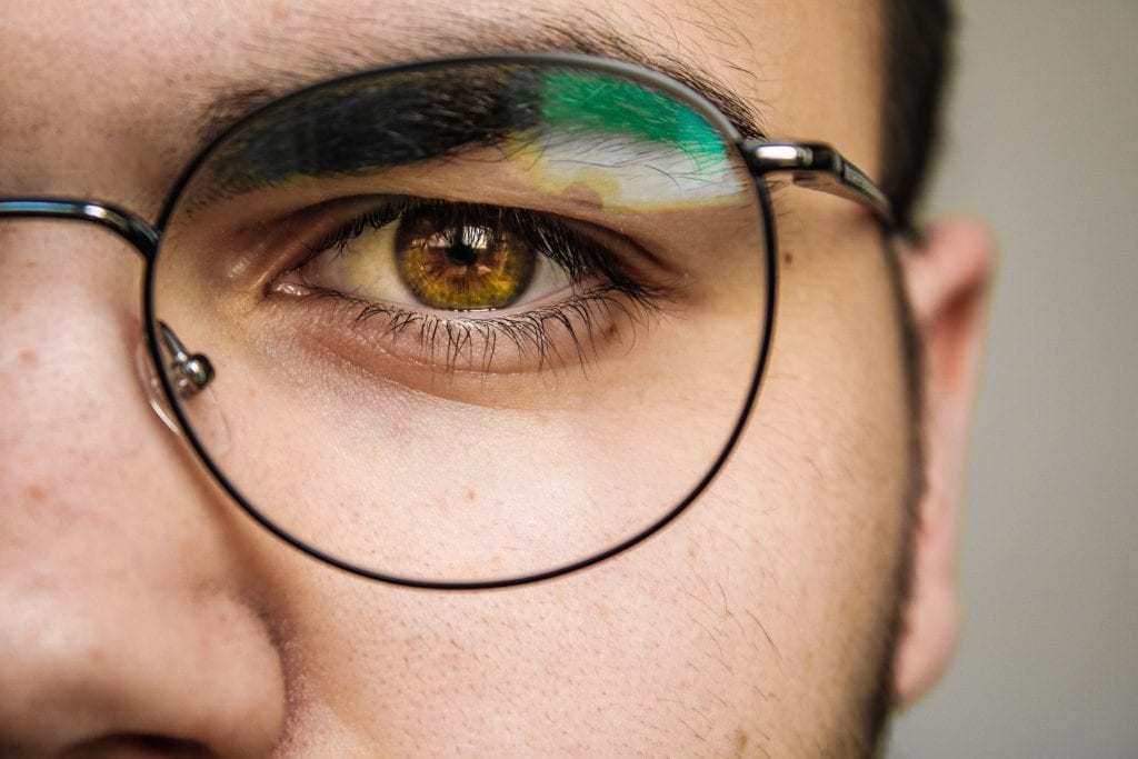 A man wearing colored contact lenses and glasses.