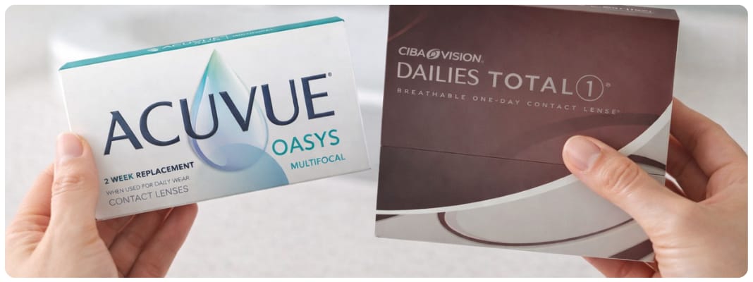 Daily vs Bi Weekly Contacts comparison showing hands holding Dailies Total1 daily lenses and ACUVUE OASYS bi-weekly lenses in a bright bathroom setting.